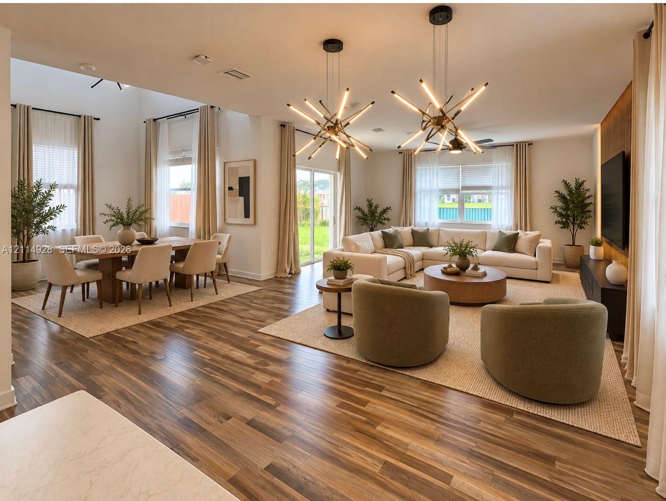Open-concept interior featuring wood-finish flooring, high ceilings, dual geometric multi-arm pendant lights, and a floor-to-ceiling wood-panel accent wall