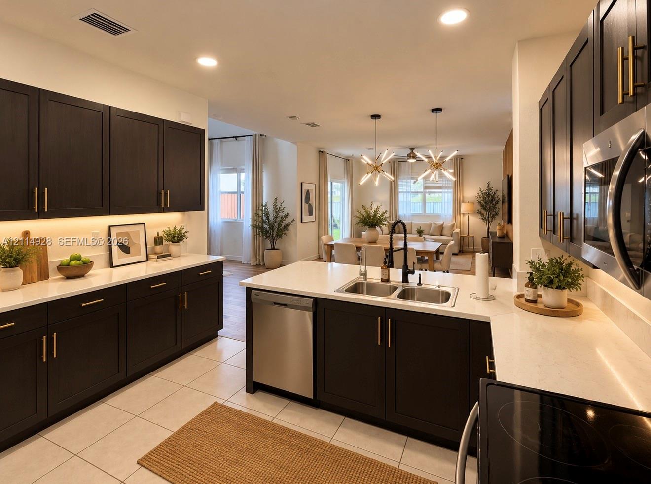 Kitchen featuring dark wood-finish cabinetry with gold-tone hardware, white stone-composite countertops, under-cabinet lighting, a stainless steel undermount sink with a matte black faucet, and recessed ceiling lighting