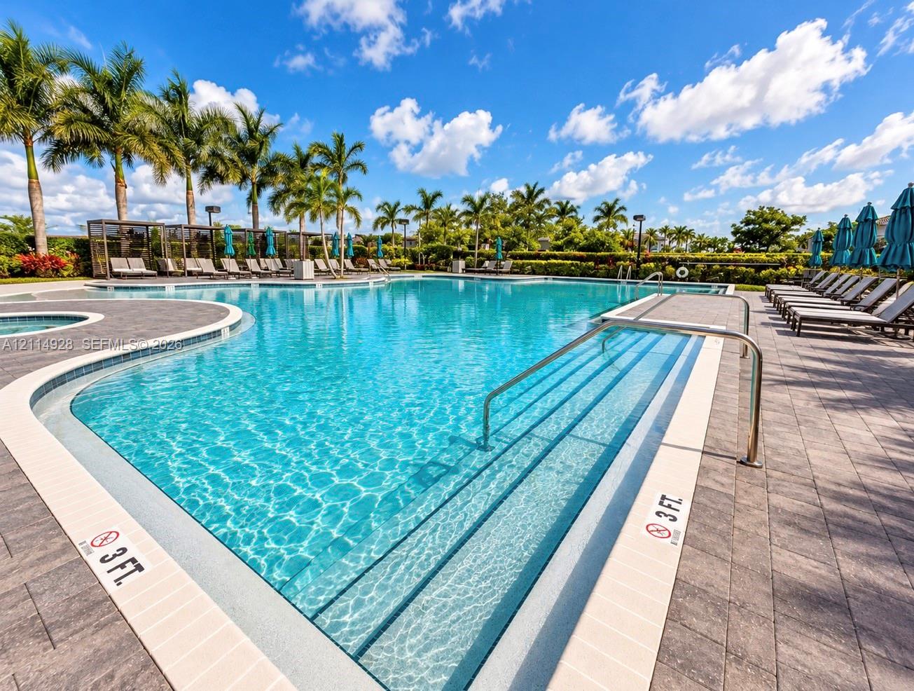 Resort-style swimming pool featuring integrated steps, paver-stone decking, and mature palm tree landscaping