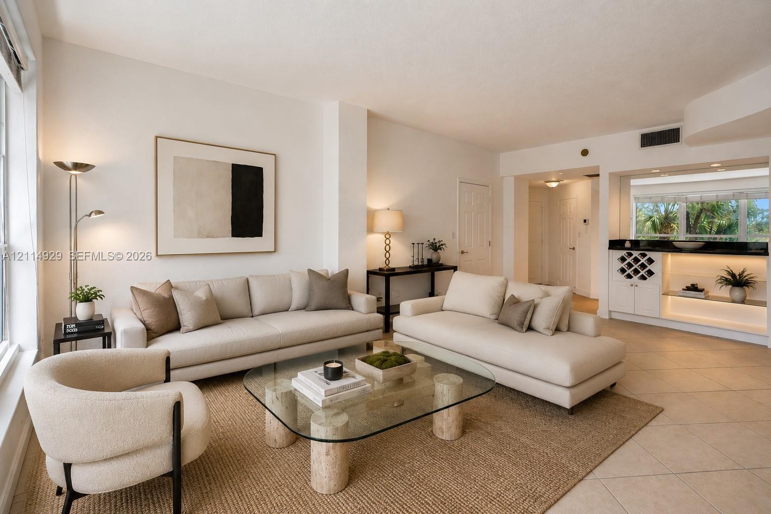 Living space featuring large-format neutral floor tile, recessed lighting, and a built-in wet bar with integrated cabinetry, wine storage, and stone-finish countertops