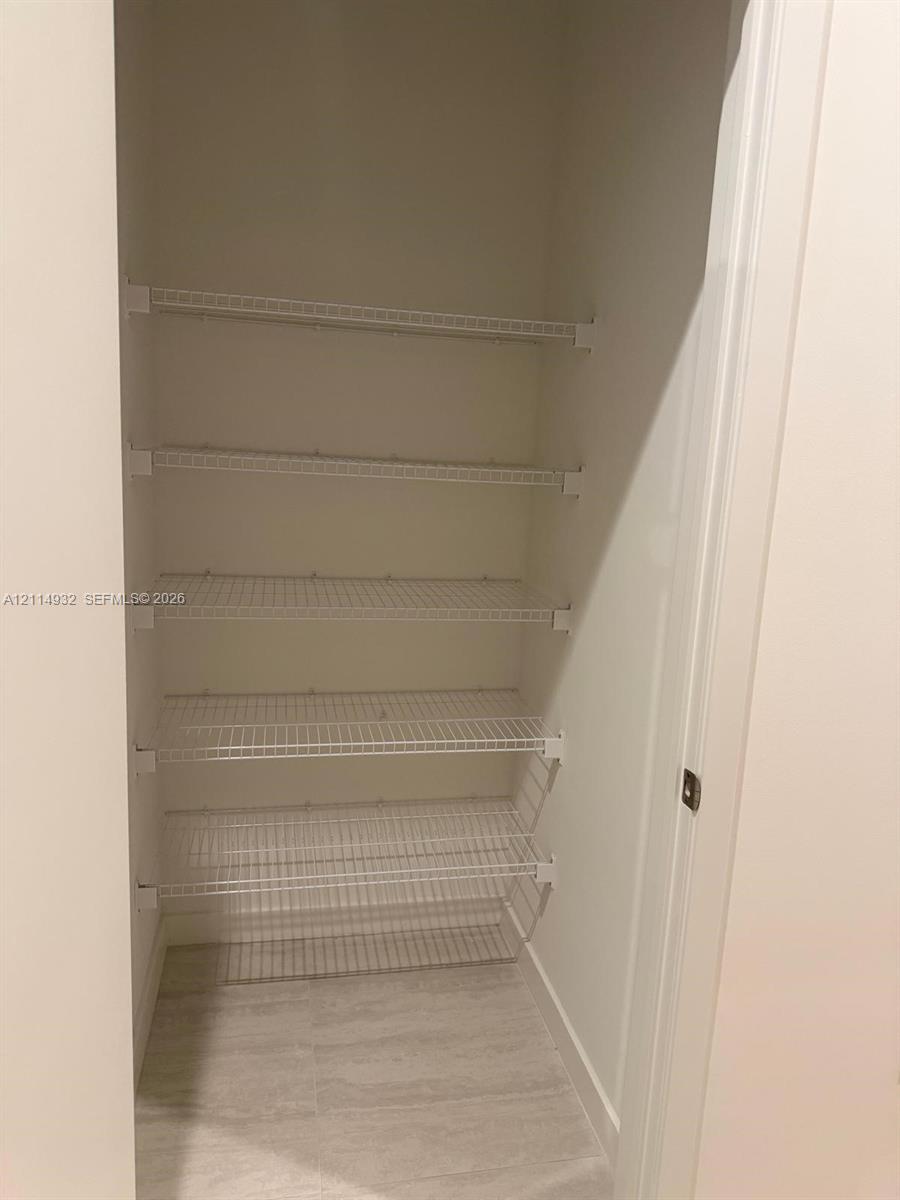 Storage space featuring five tiers of white wire shelving and tile flooring