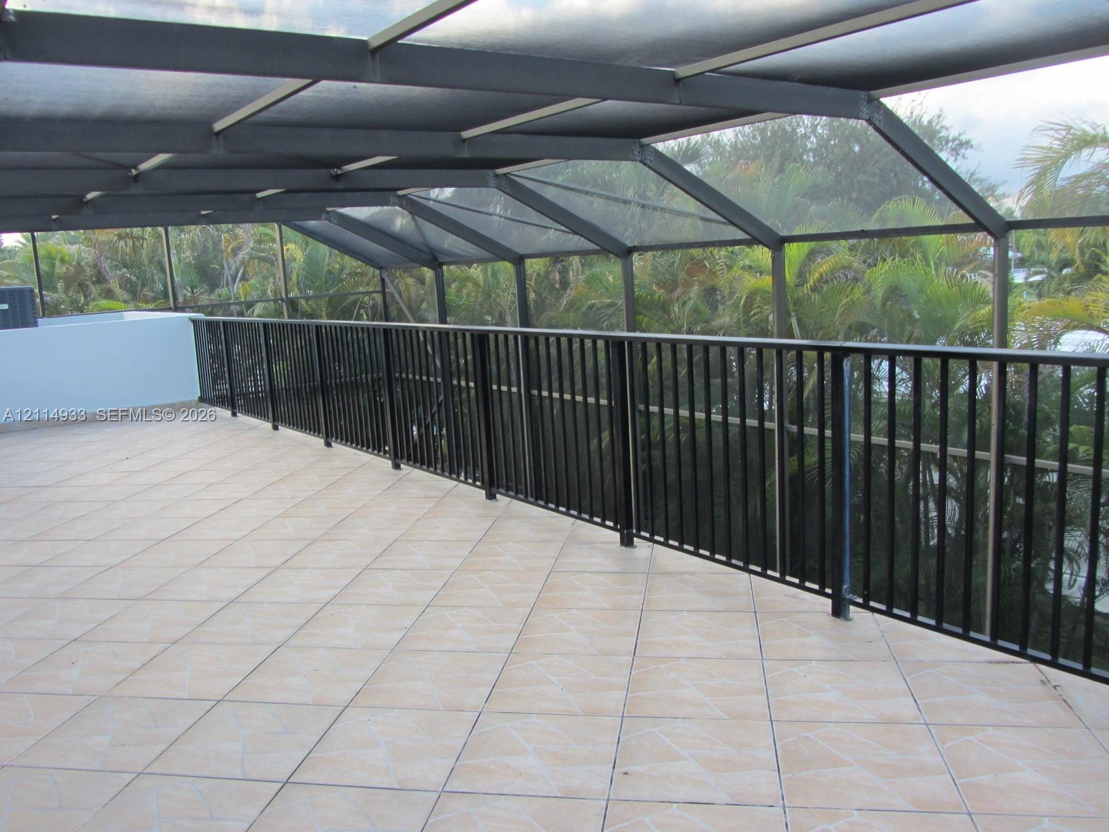 Screened-in balcony featuring tile flooring, metal structural framing, and a black vertical-slat railing
