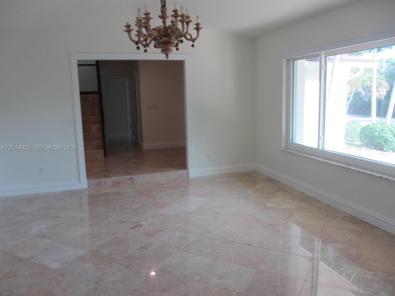 Polished stone tile flooring, ornate multi-arm chandelier, and expansive picture window Polished stone tile flooring, ornate multi-arm chandelier, and expansive picture window