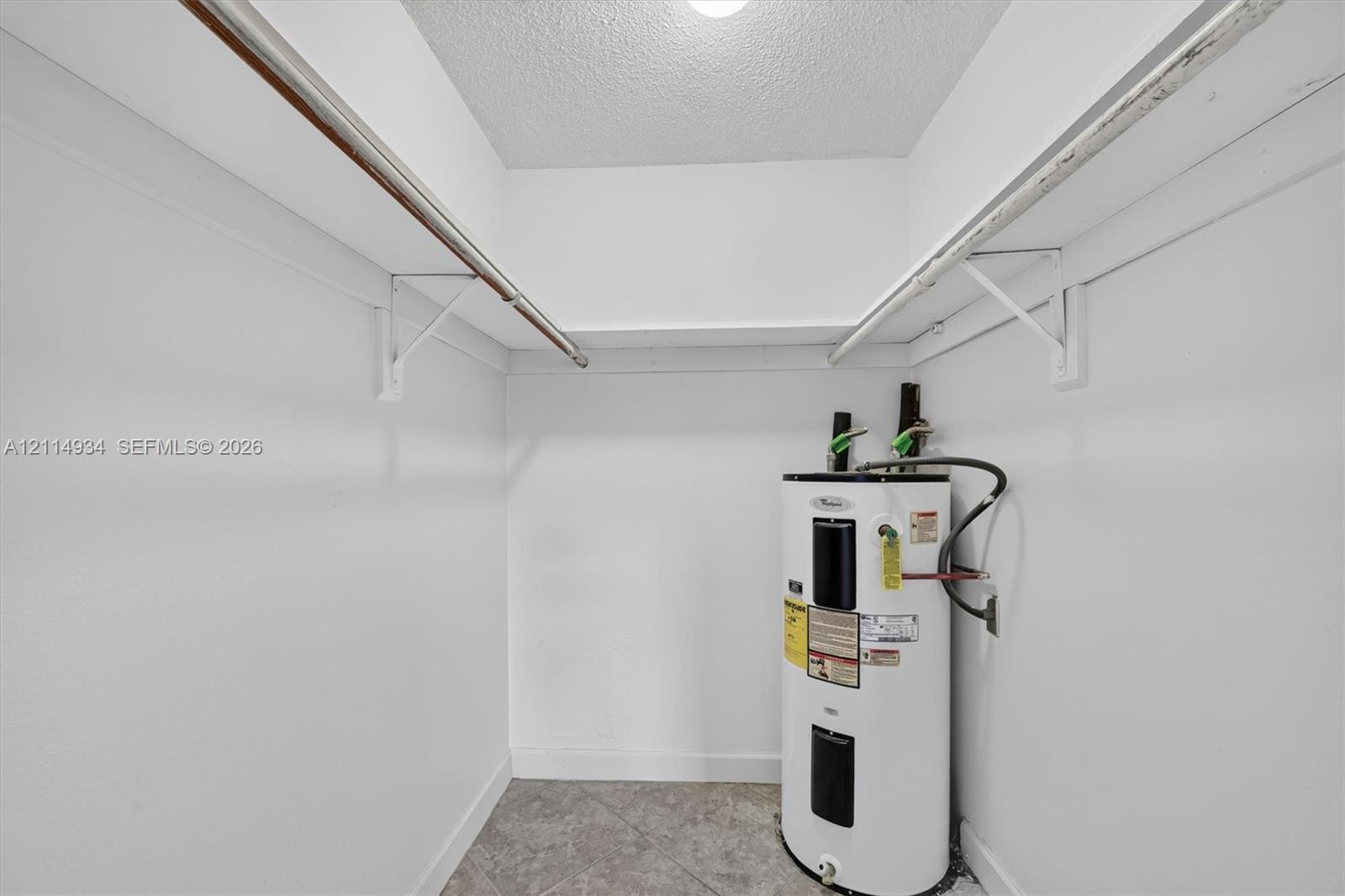 Utility closet featuring tiled flooring, white walls, and built-in metal shelving rods
