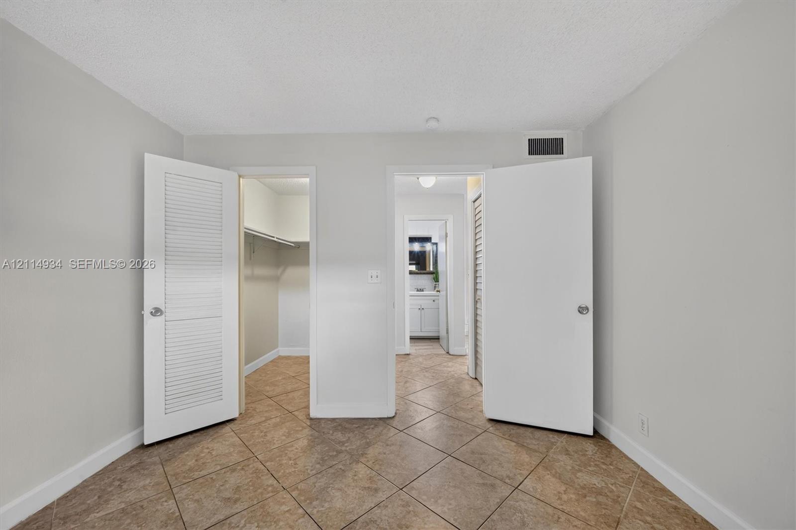 Tile flooring, neutral wall tones, and dual louvered-style closet doors