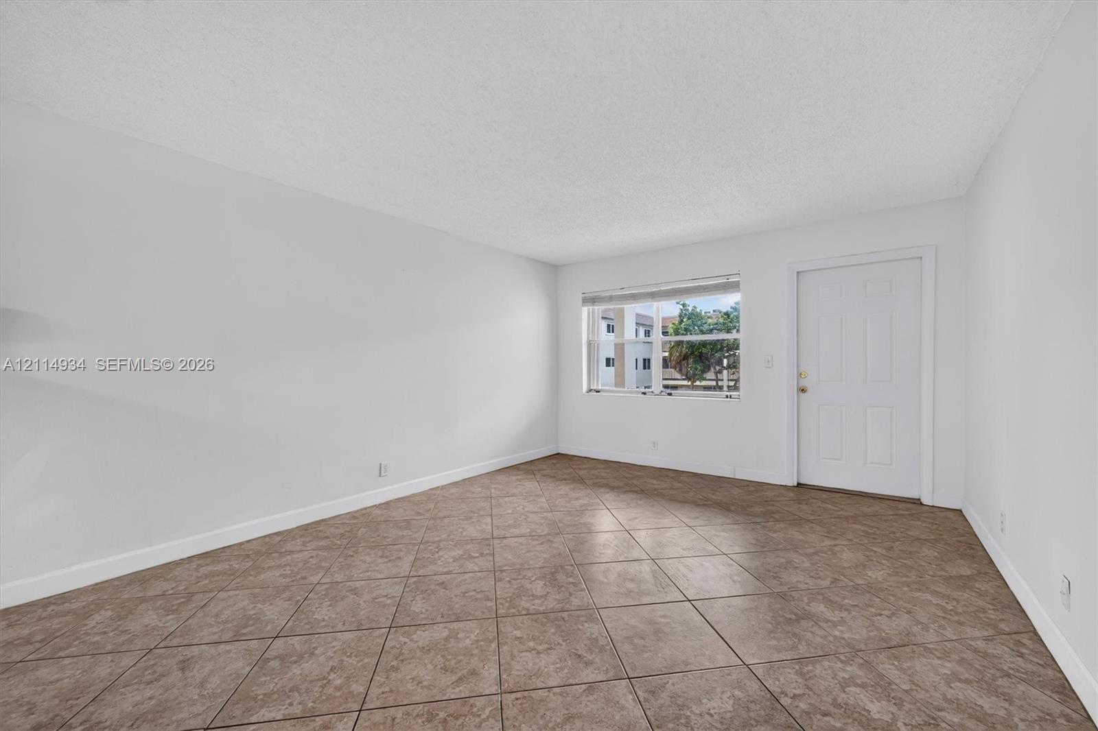 Neutral-toned room featuring diagonal-set tile flooring, white walls, and a recessed window with horizontal blinds