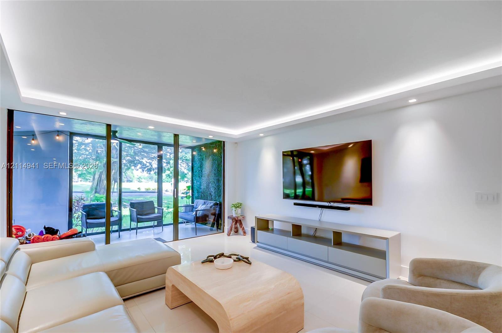 Living area featuring large-format tile flooring, recessed tray ceiling lighting, and floor-to-ceiling sliding glass doors Living area featuring large-format tile flooring, recessed tray ceiling lighting, and floor-to-ceiling sliding glass doors