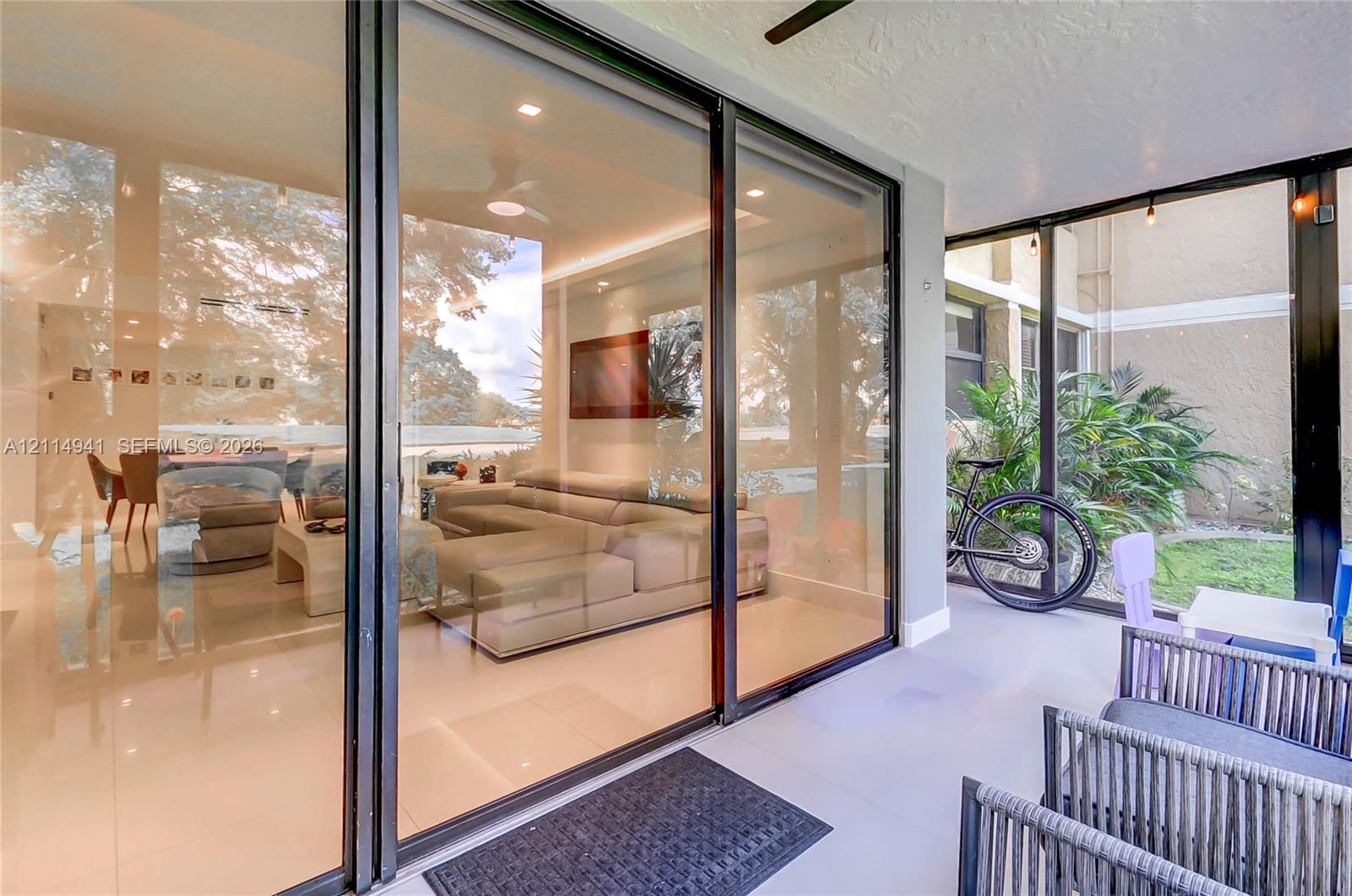 Enclosed patio with full-height black-frame glass sliders, recessed ceiling lighting, and tile flooring