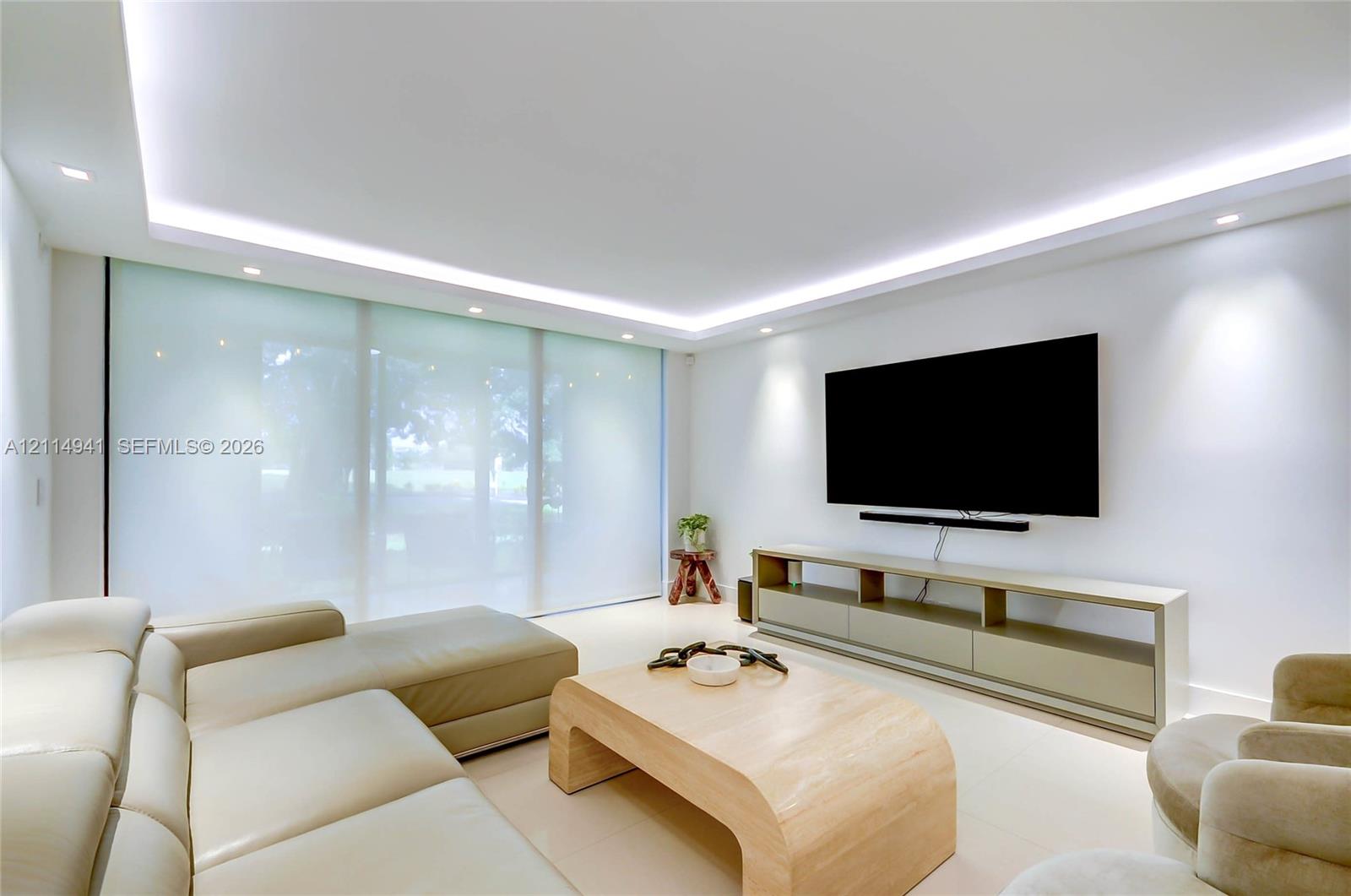 Tray ceiling featuring recessed LED lighting, expansive floor-to-ceiling glass wall panels, smooth finish flooring, and integrated wall-mounted lighting Tray ceiling featuring recessed LED lighting, expansive floor-to-ceiling glass wall panels, smooth finish flooring, and integrated wall-mounted lighting