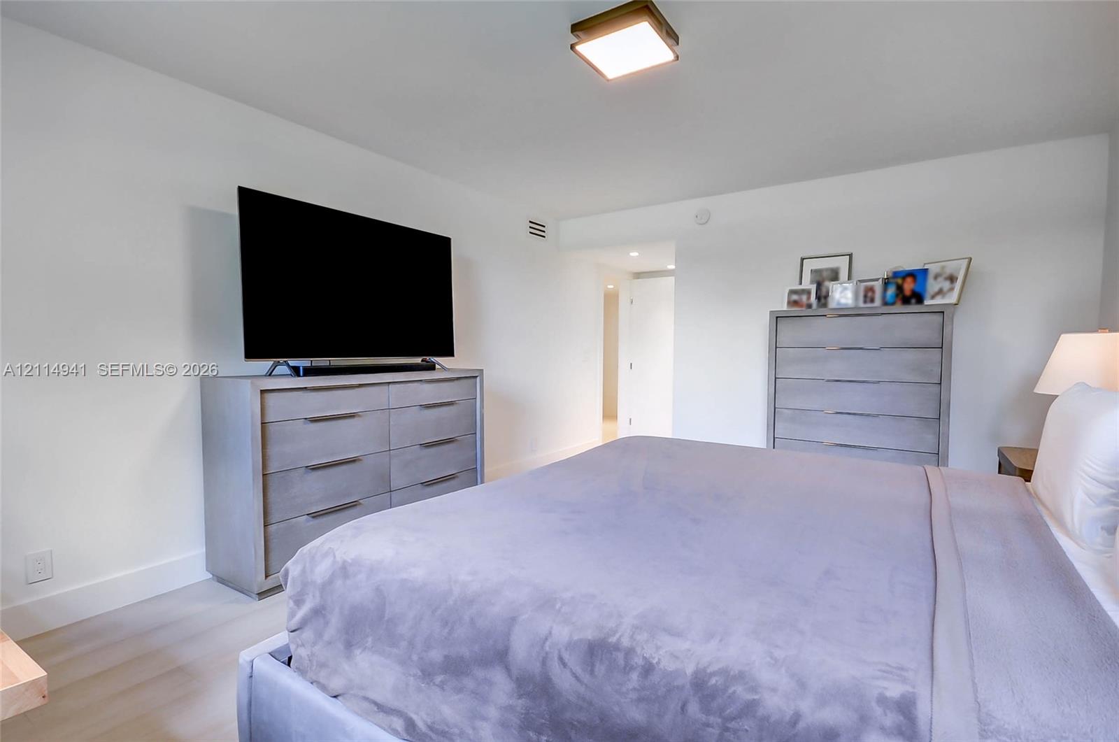 Neutral color palette featuring light-toned wood-finish flooring and a ceiling-mounted square light fixture