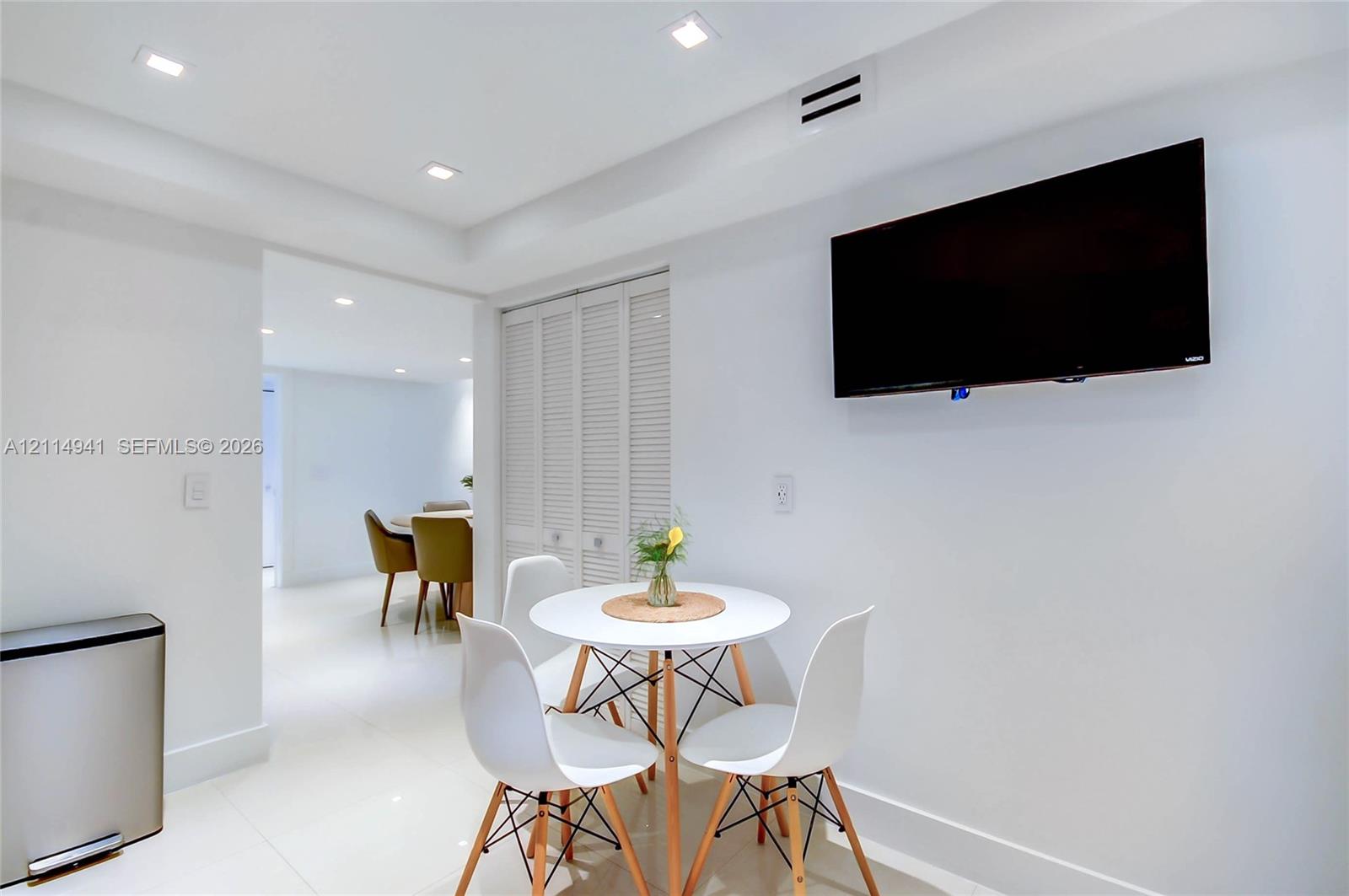 Recessed ceiling lighting, glossy tile flooring, and bi-fold louvered closet doors