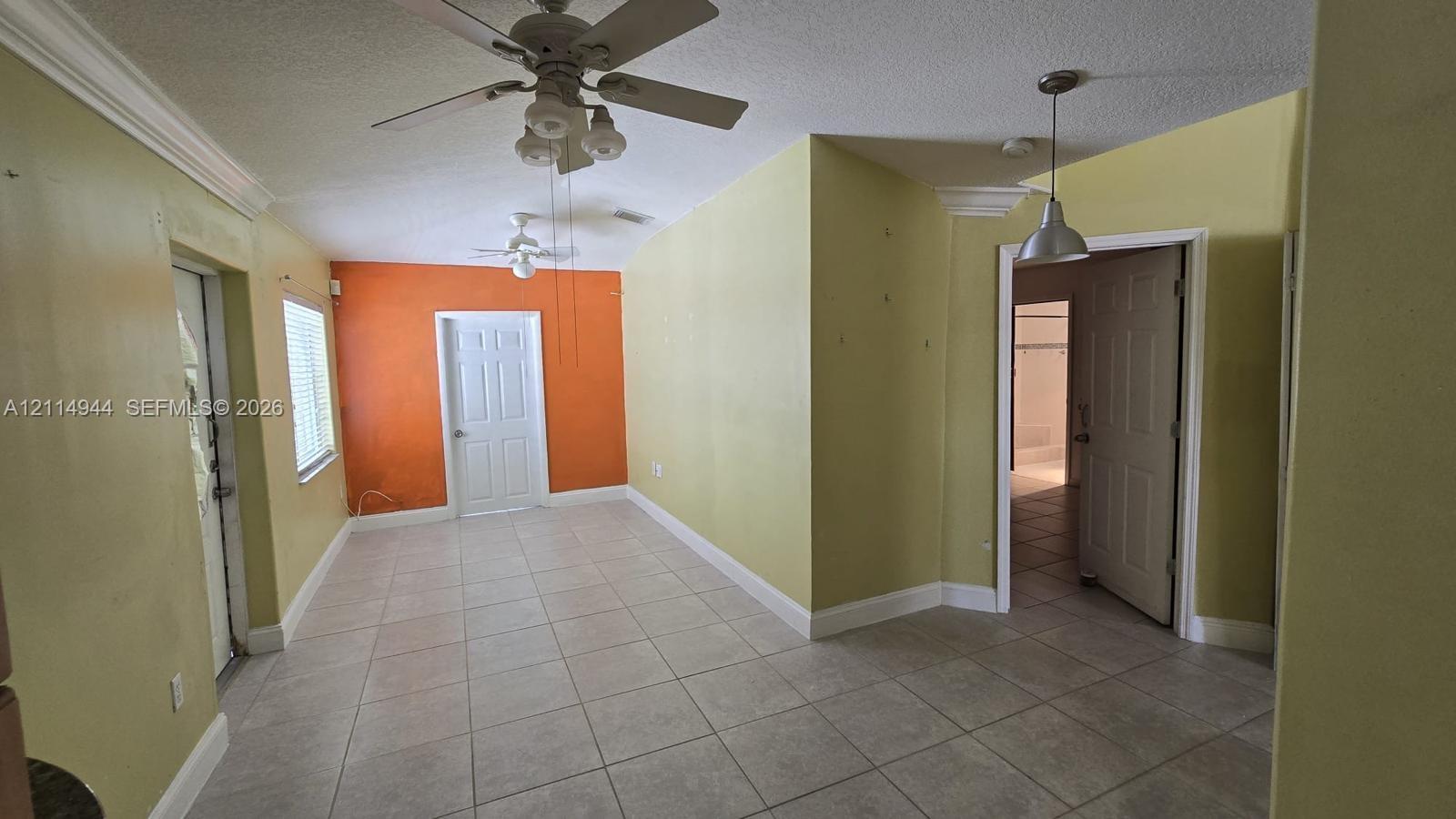 Interior space featuring light-colored tile flooring, multiple ceiling fans, recessed crown molding, and hanging pendant lighting