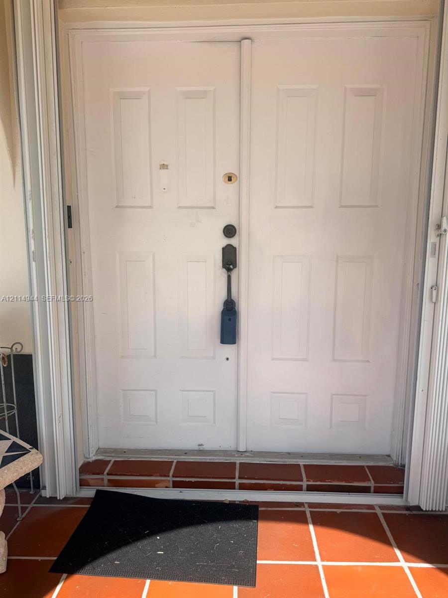 Double-door entry featuring white recessed-panel doors and a terracotta tile threshold