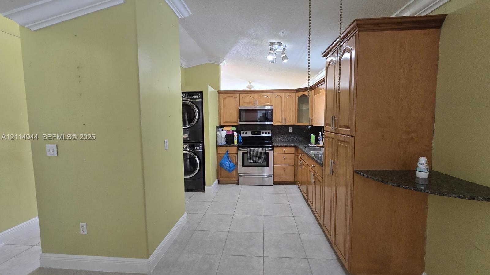 Kitchen featuring shaker-style cabinetry, stone countertops, stainless steel appliances, a built-in microwave, and tile flooring