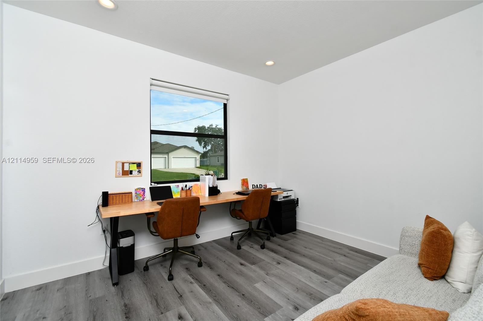 Neutral-toned interior space featuring wood-finish flooring, recessed lighting, and a window with a black frame