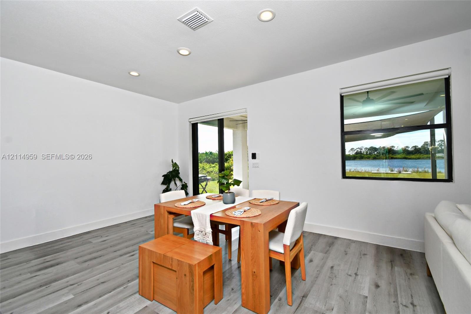 Wood-finish flooring, recessed lighting, sliding glass door, and picture window featuring water scenery