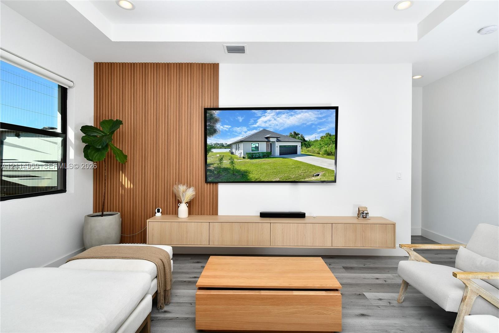 Living area featuring a vertical wood-slat accent wall, floating cabinetry, recessed ceiling lighting, and wood-finish flooring