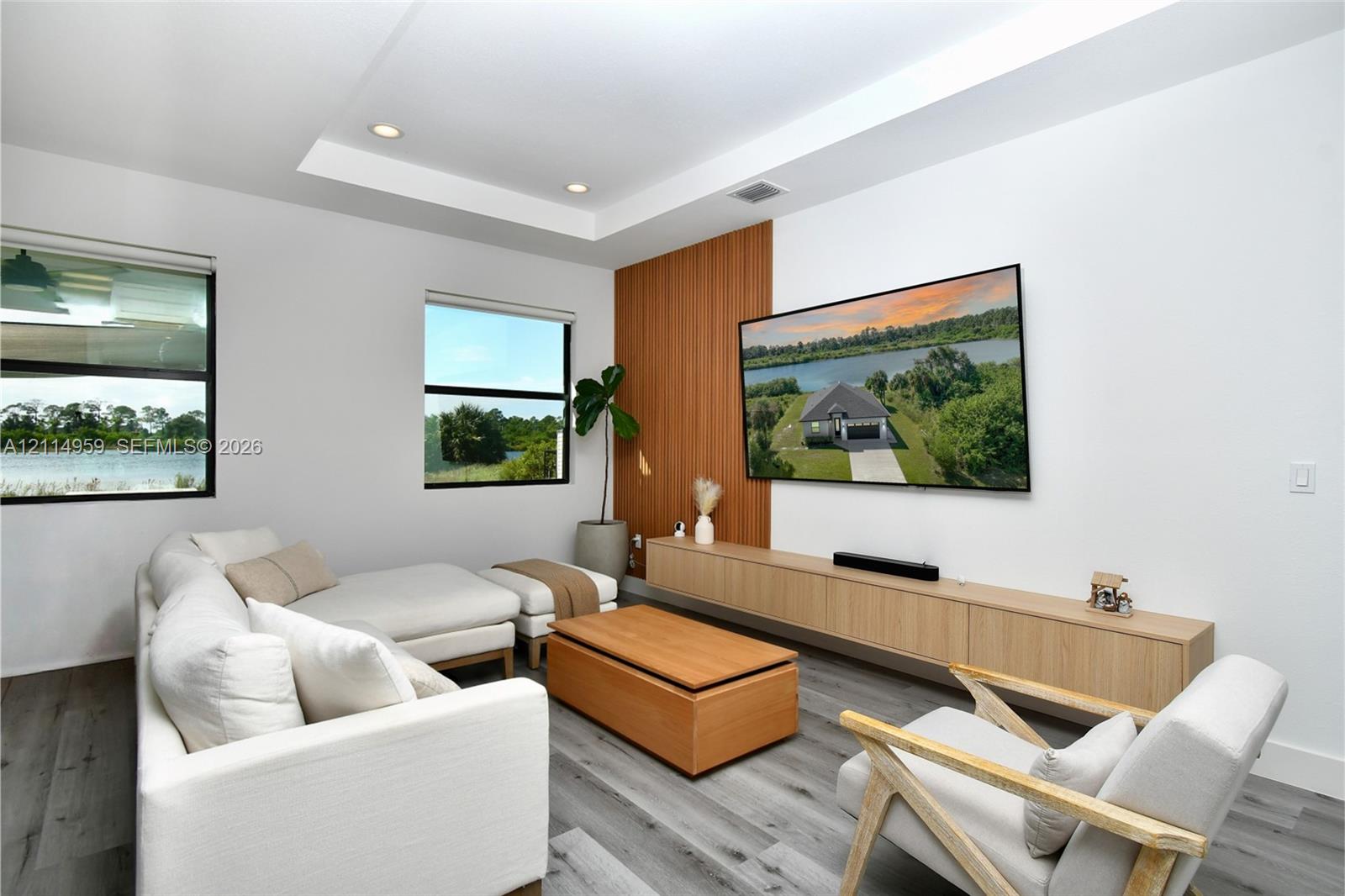 Tray ceiling with recessed lighting, wood-finish flooring, floor-to-ceiling wood-panel accent wall, and wall-mounted light wood cabinetry