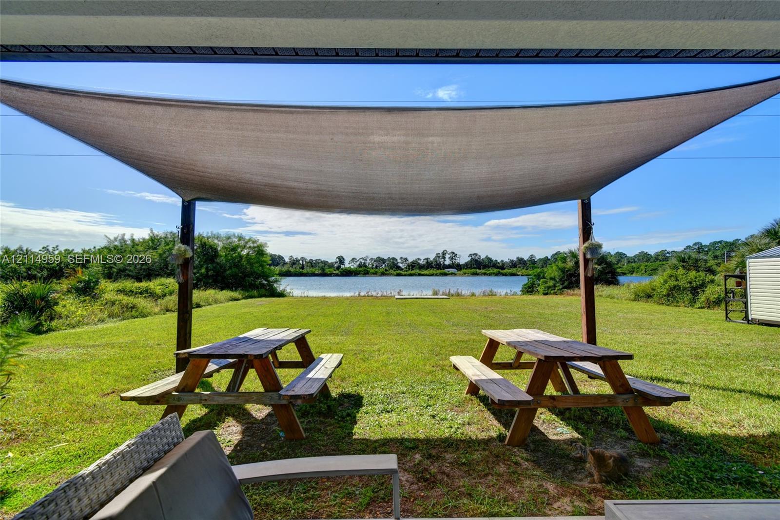 Covered outdoor space featuring a fabric shade canopy, expansive lawn, and waterfront footage