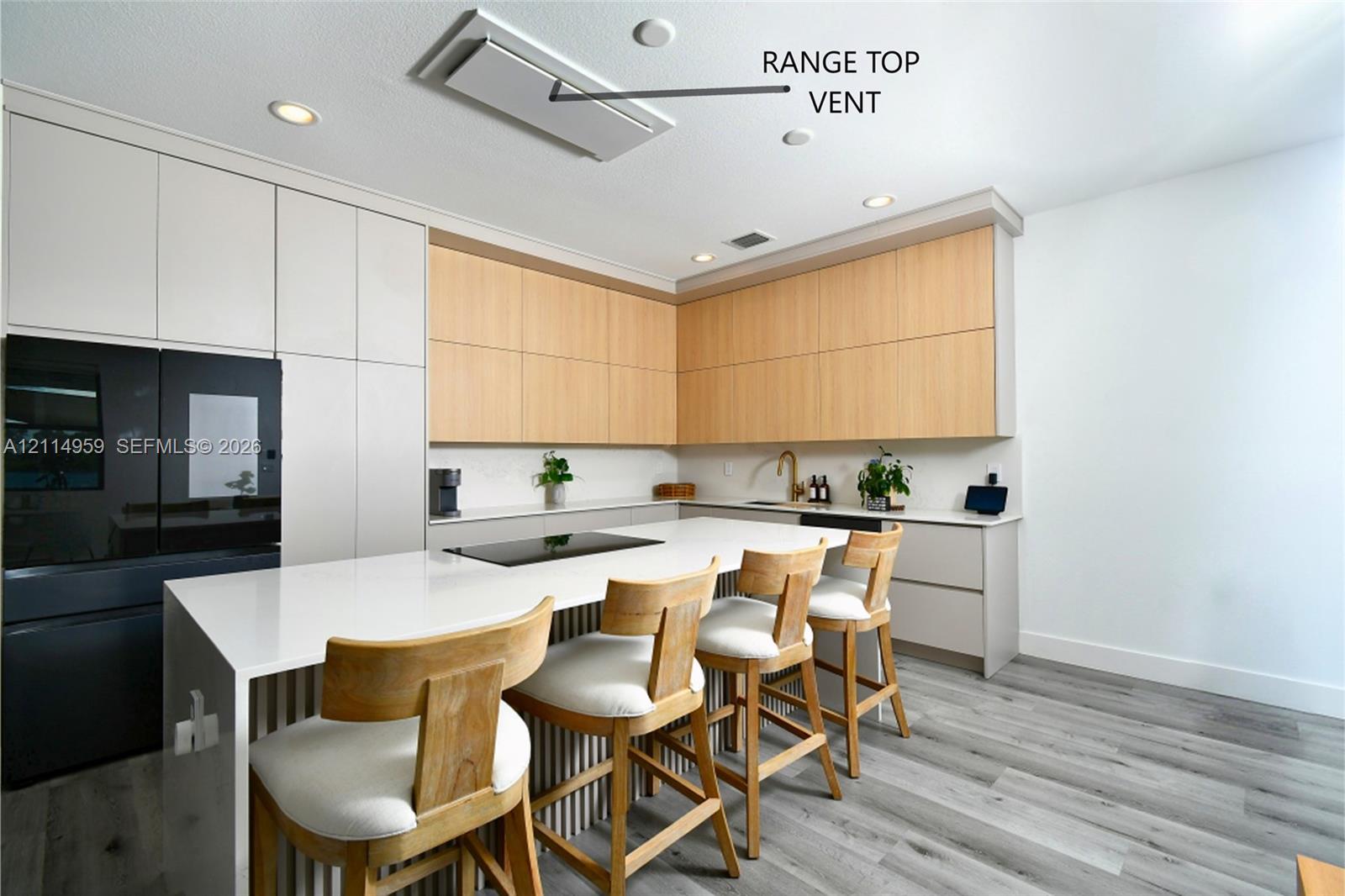 Kitchen featuring two-tone cabinetry with wood-finish upper units, quartz countertops, a flush-mount ceiling vent, recessed lighting, and wood-finish flooring