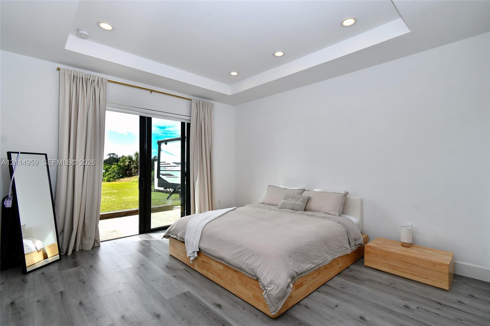 Tray ceiling with recessed lighting, wood-finish flooring, and expansive black-framed sliding glass doors