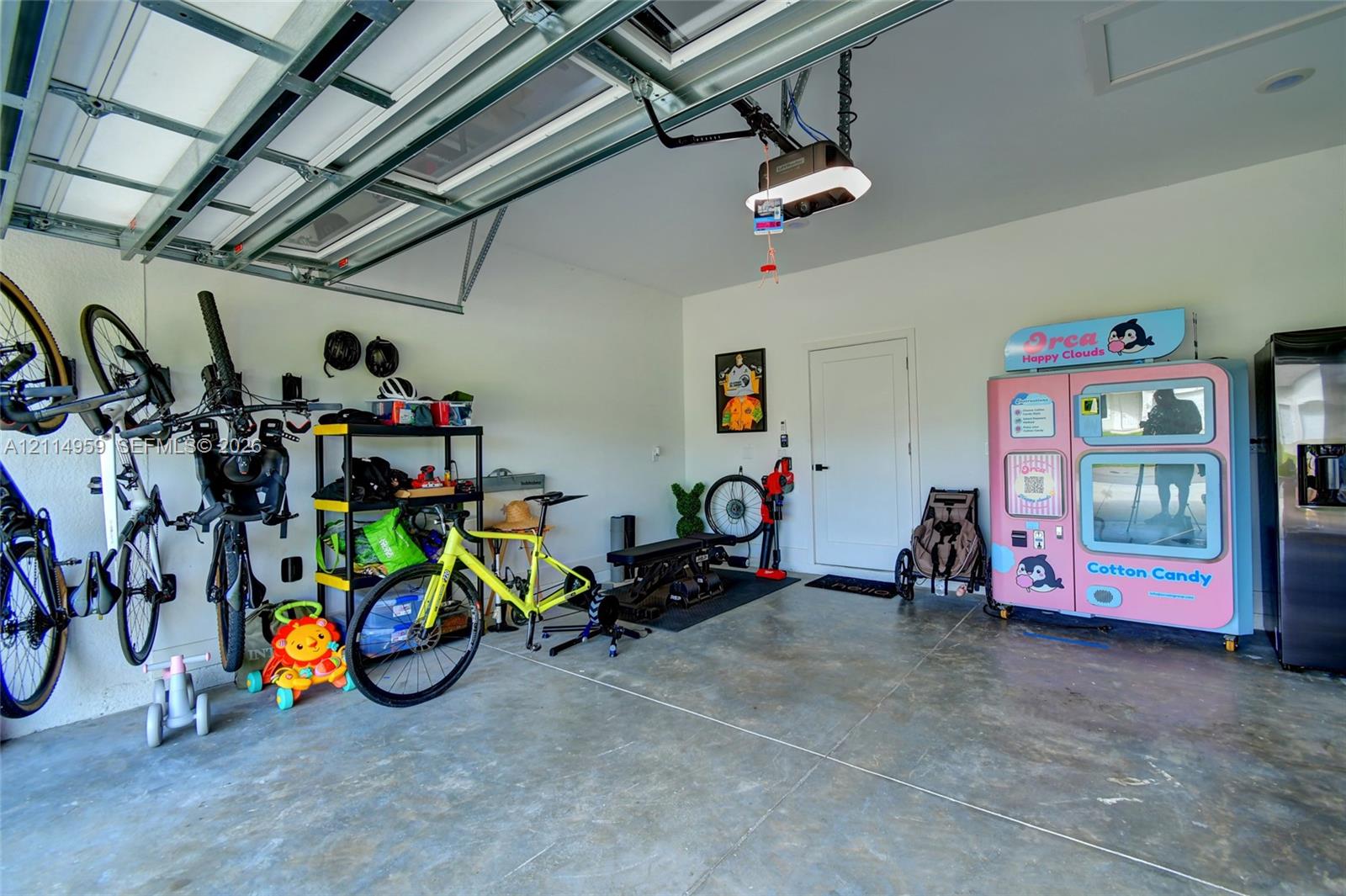 Attached two-car garage featuring a concrete floor, finished white walls, and a motorized overhead door opener