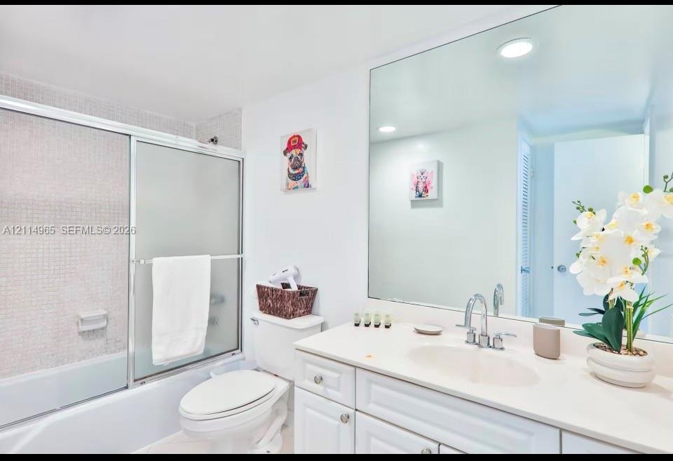 Bathroom featuring a white vanity with an integrated oval basin, a chrome widespread faucet, a full-width wall mirror, and a shower-tub combination with sliding glass doors and mosaic tile surround