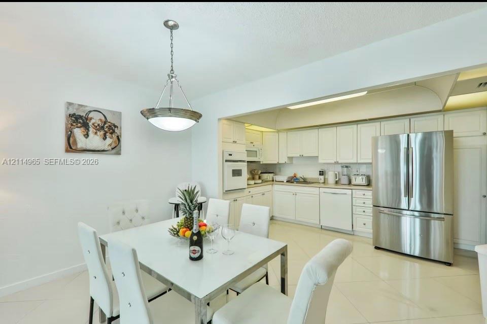 Kitchen featuring white cabinetry, solid-surface countertops, stainless steel appliances, a built-in wall oven, and light-toned tile flooring