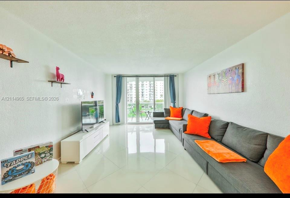 Living space featuring polished tile flooring, neutral walls, and a multi-panel glass door providing natural light