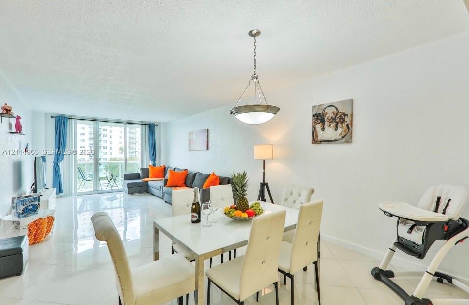 Open-concept living space featuring high-gloss tile flooring, an oversized sliding glass door, and a multi-light metal pendant fixture