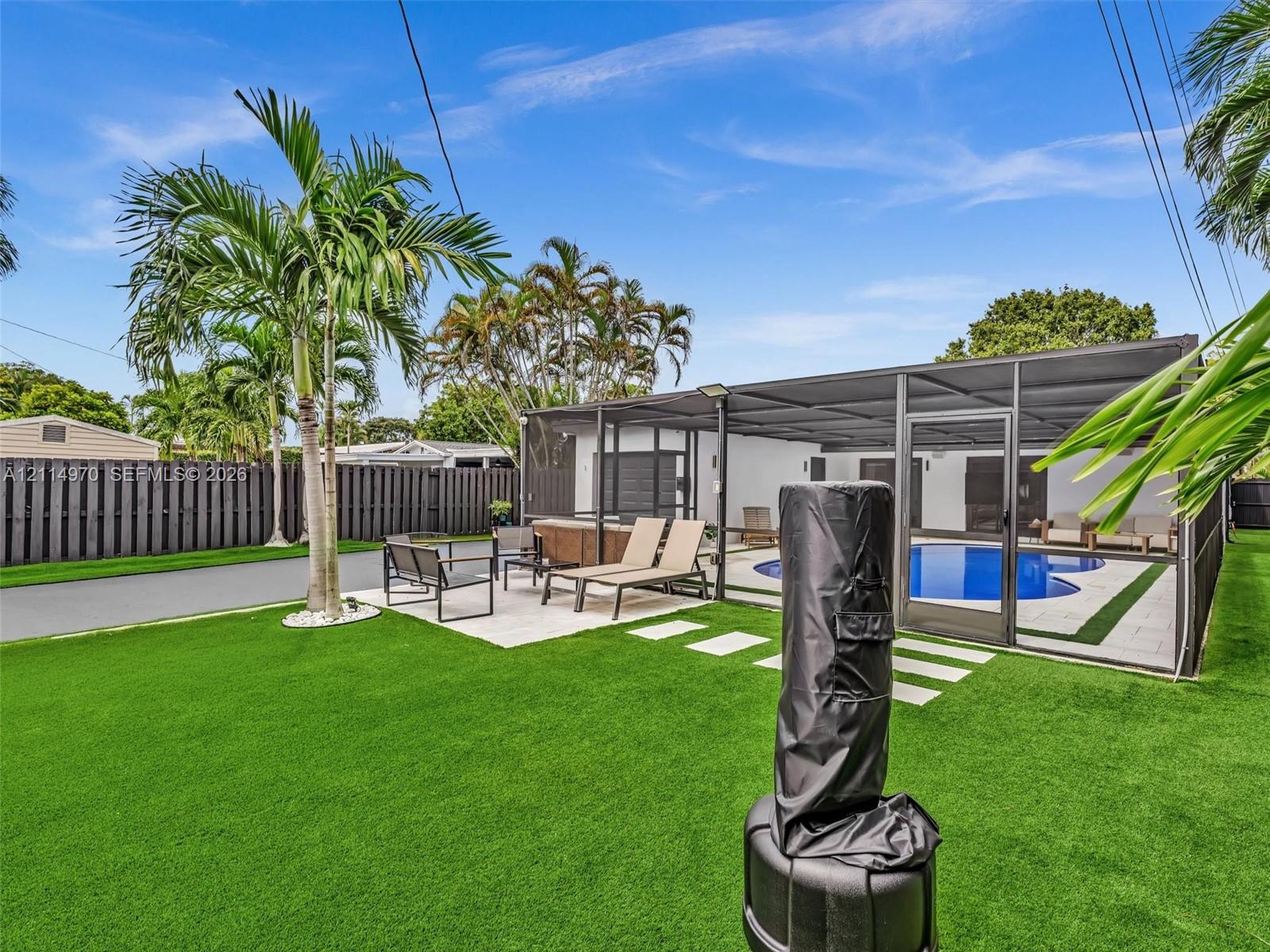 Backyard featuring synthetic turf, screened-in swimming pool, paved patio, and privacy fencing