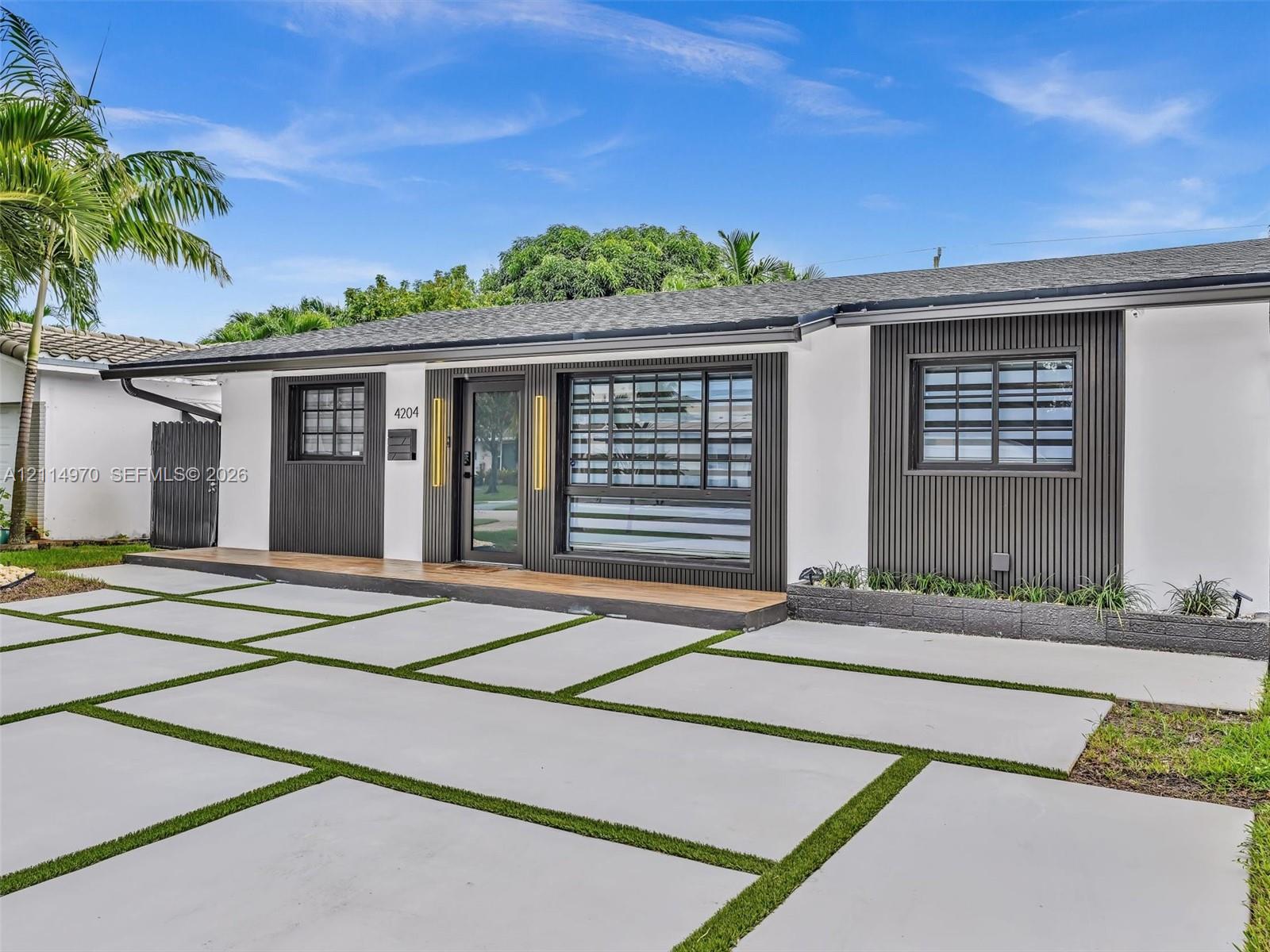 Contemporary exterior featuring smooth white stucco, vertical dark-tone siding accents, custom multi-pane window configurations, and a concrete paver driveway with integrated grass joints