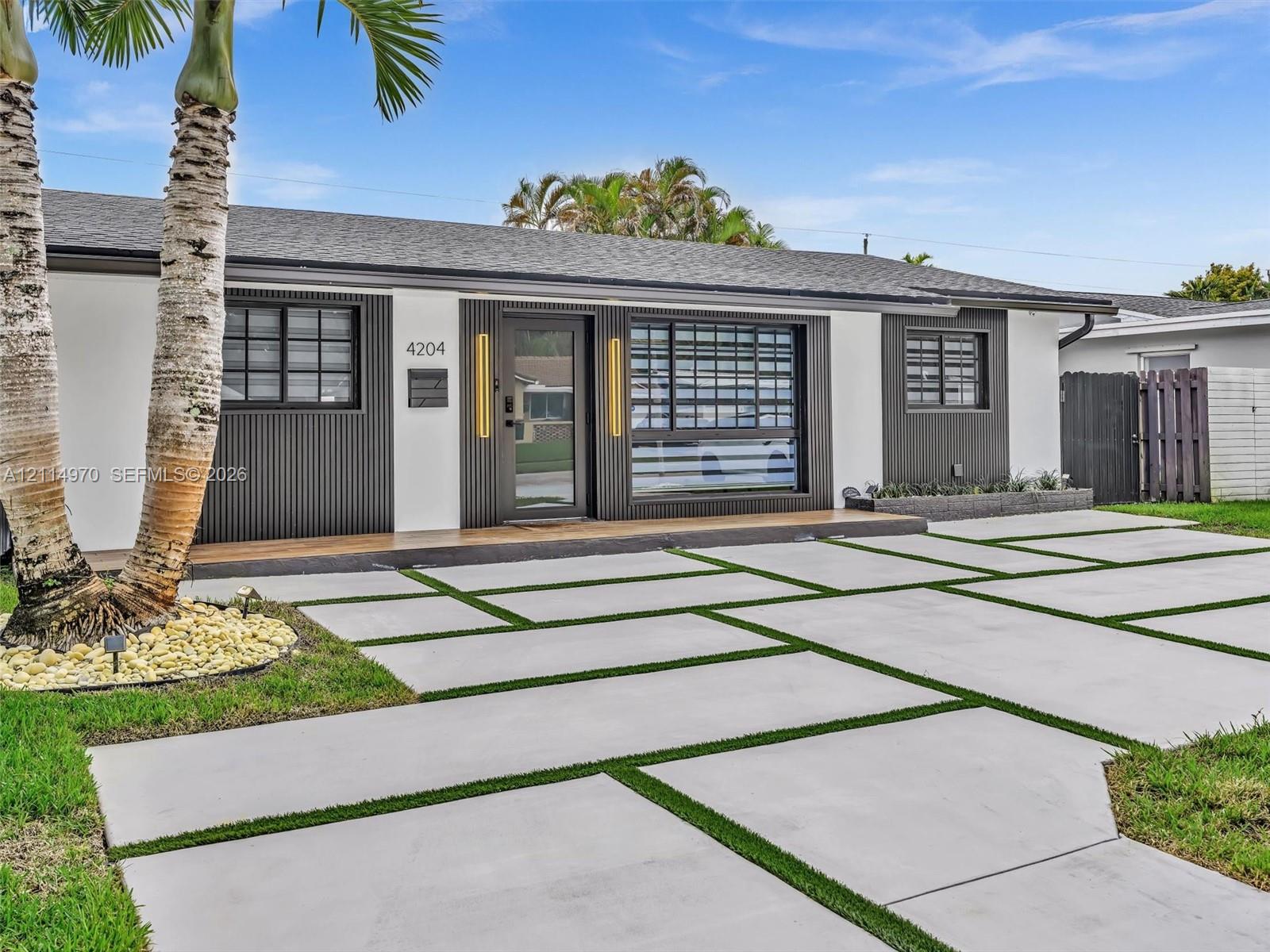Contemporary exterior featuring a contrasting facade of white stucco and dark vertical slat detailing, geometric concrete paver driveway with turf inserts, and low-profile hardscaping