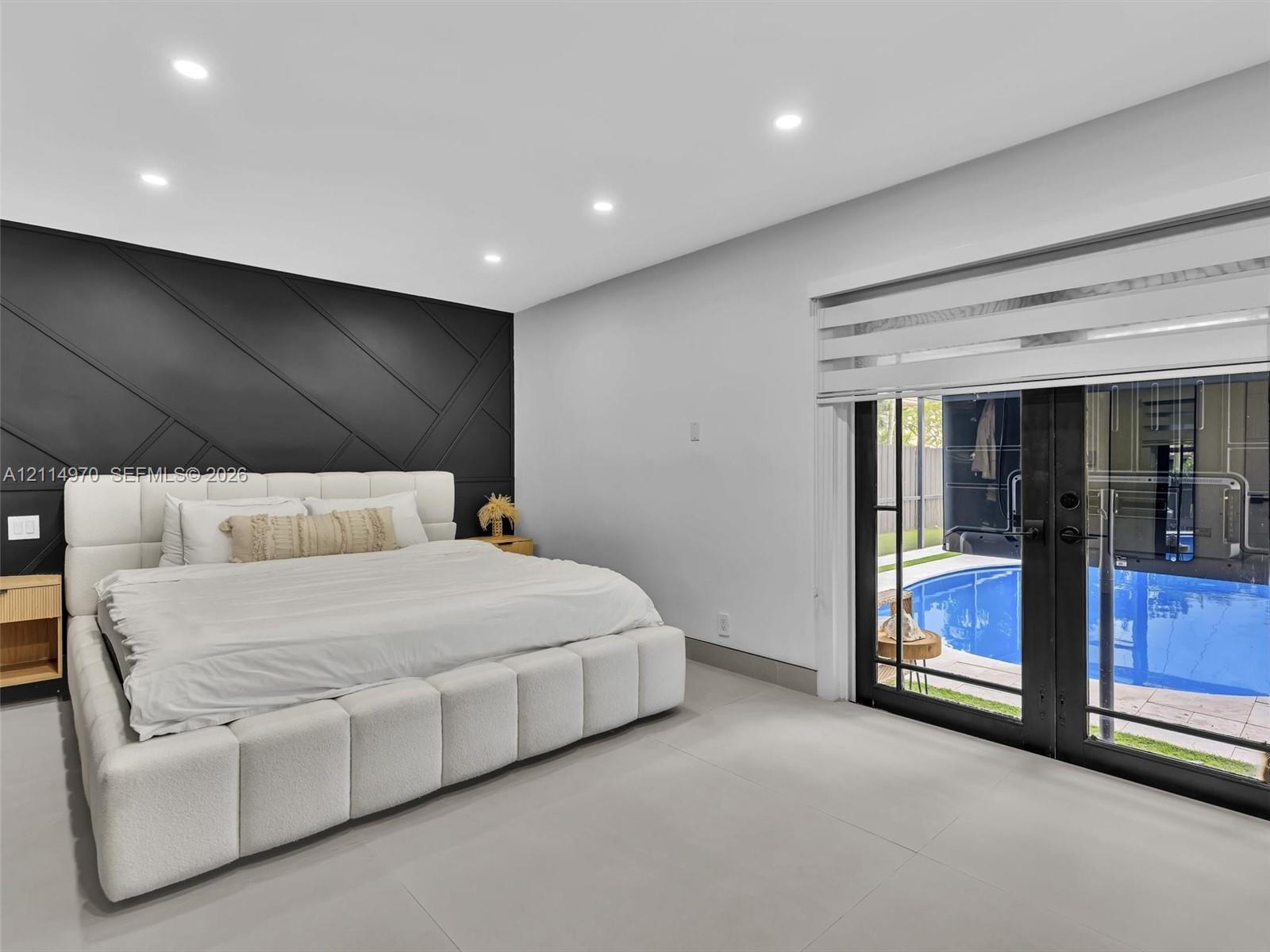Geometric black accent wall, recessed ceiling lighting, large-format tile flooring, and glass-paneled double doors featuring an exterior swimming pool
