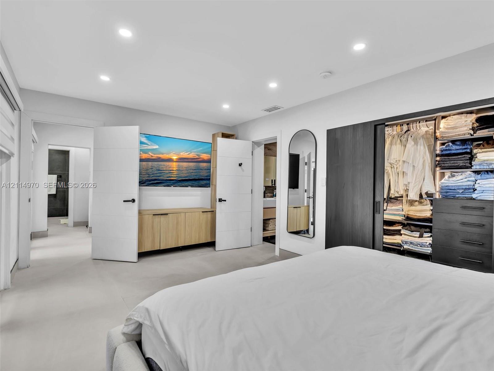 Recessed lighting, built-in light-wood cabinetry, matte black hardware, and floor-to-ceiling closet with dark-finish sliding doors