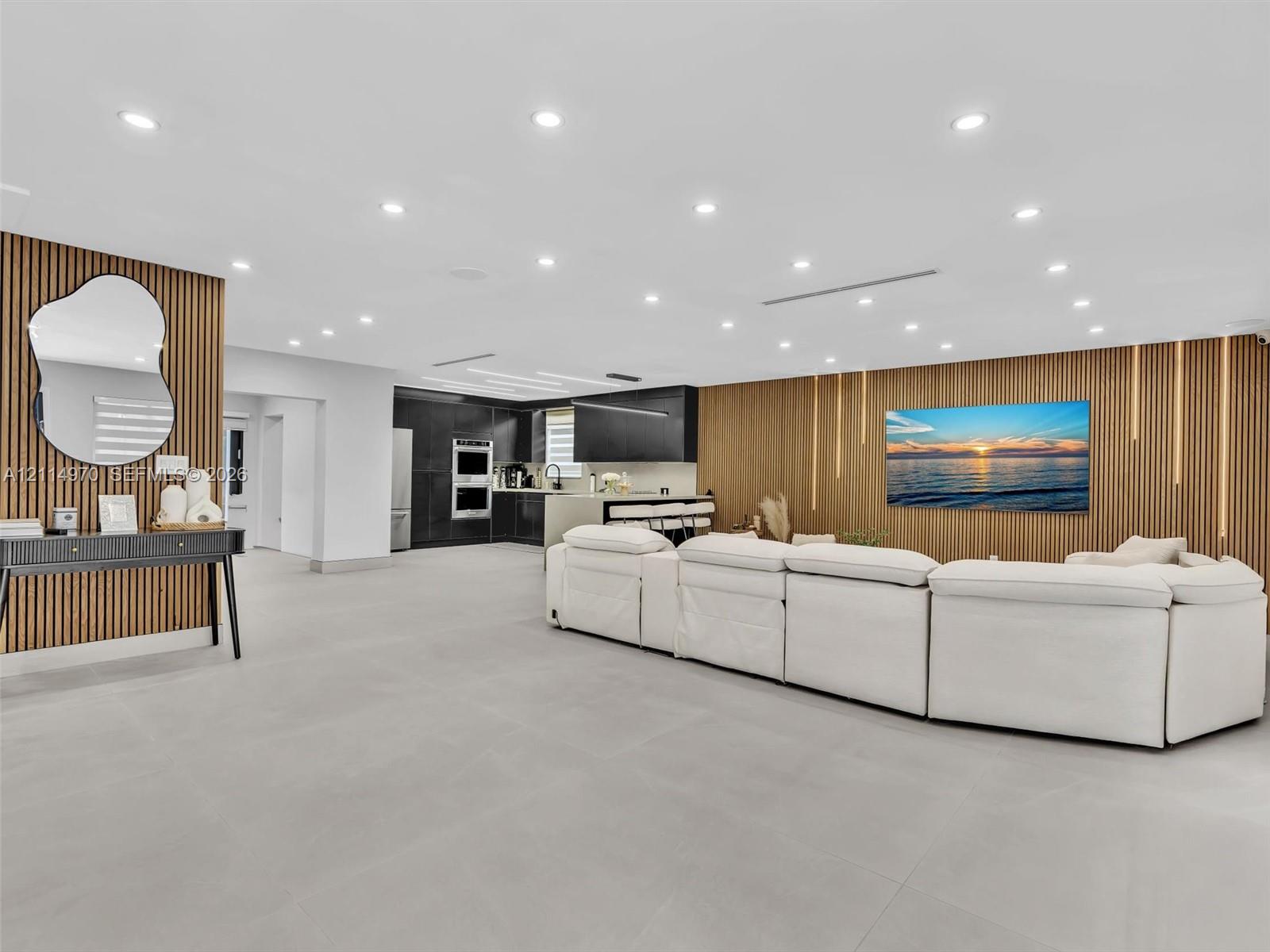 Open-concept interior featuring large-format tile flooring, recessed ceiling lighting, and custom wood-slat accent walls