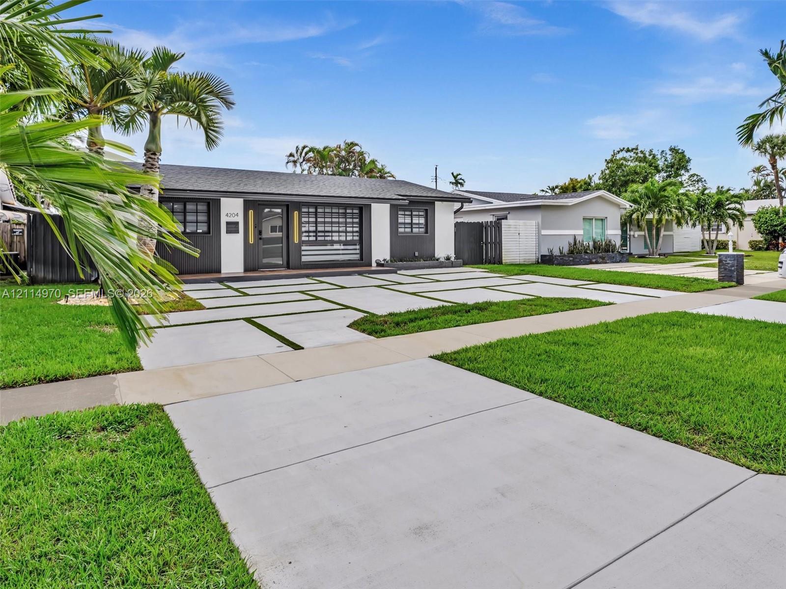 Exterior featuring a contemporary concrete paver driveway with integrated turf, dark-toned siding with contrasting white trim, and a multi-lite front door
