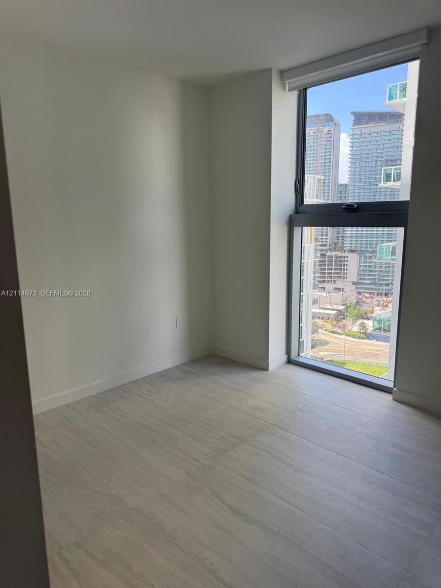 Neutral interior space featuring large-format tile flooring, floor-to-ceiling windows, and urban cityscape backdrop