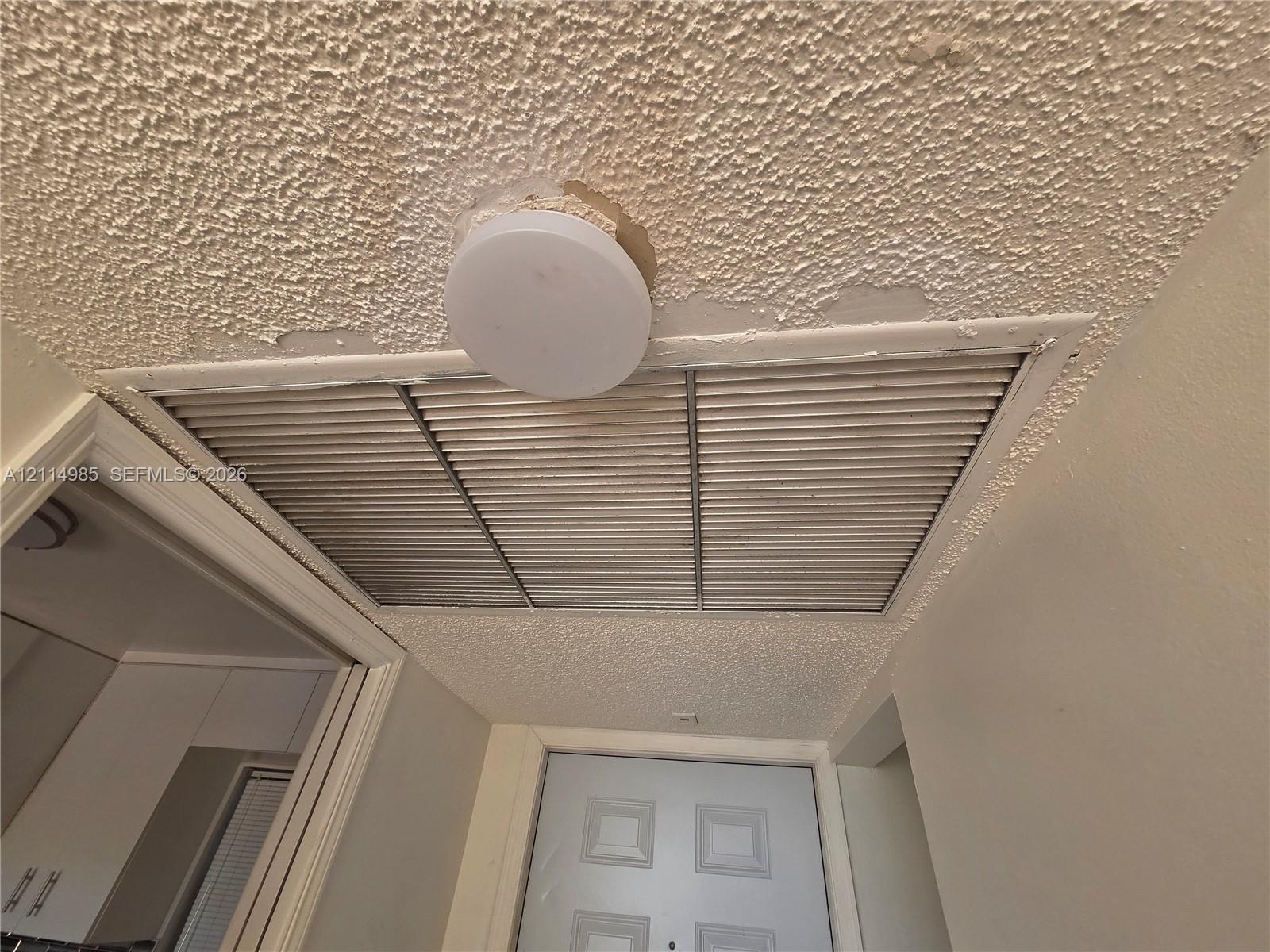 Flush-mount ceiling lighting fixture, textured ceiling finish, and louvered HVAC return grille