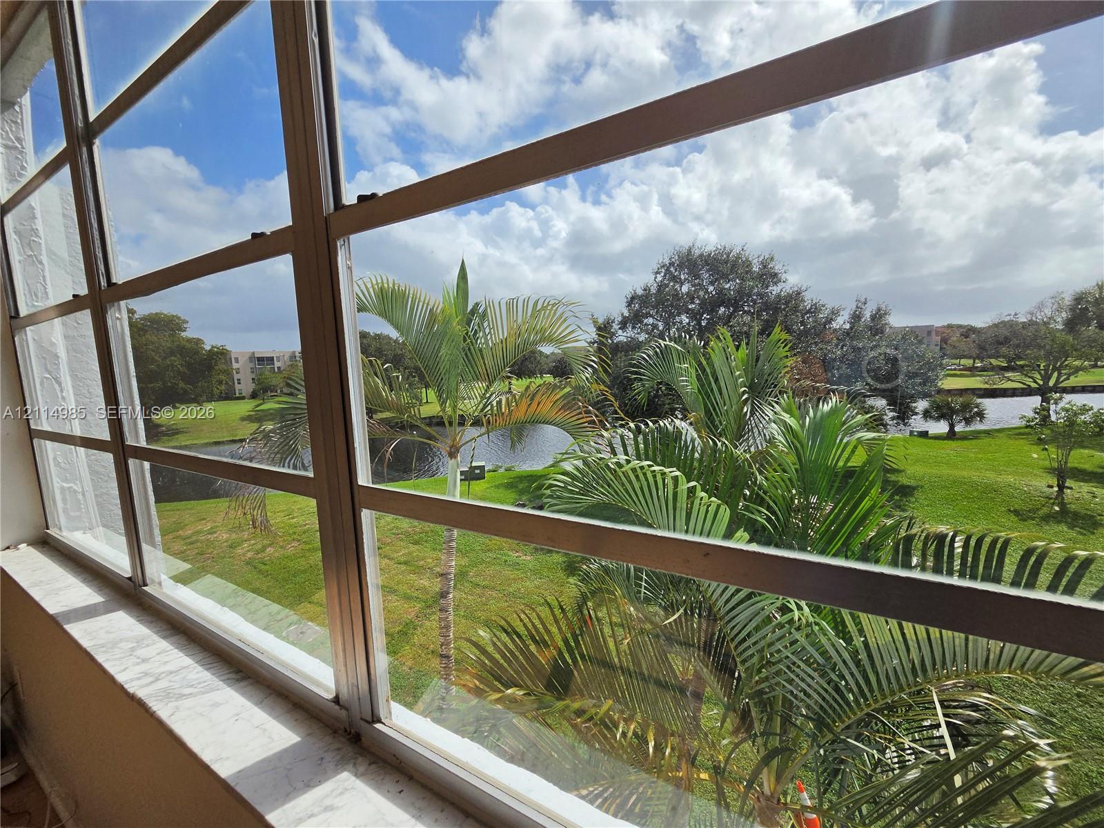Multi-pane window featuring a smooth-finish sill, showcasing exterior water frontage, mature palm trees, and manicured green space