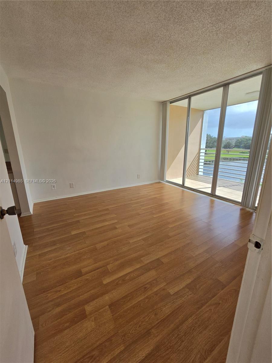 Wood-finish flooring, full-height sliding glass doors, and an outdoor balcony with metal railing