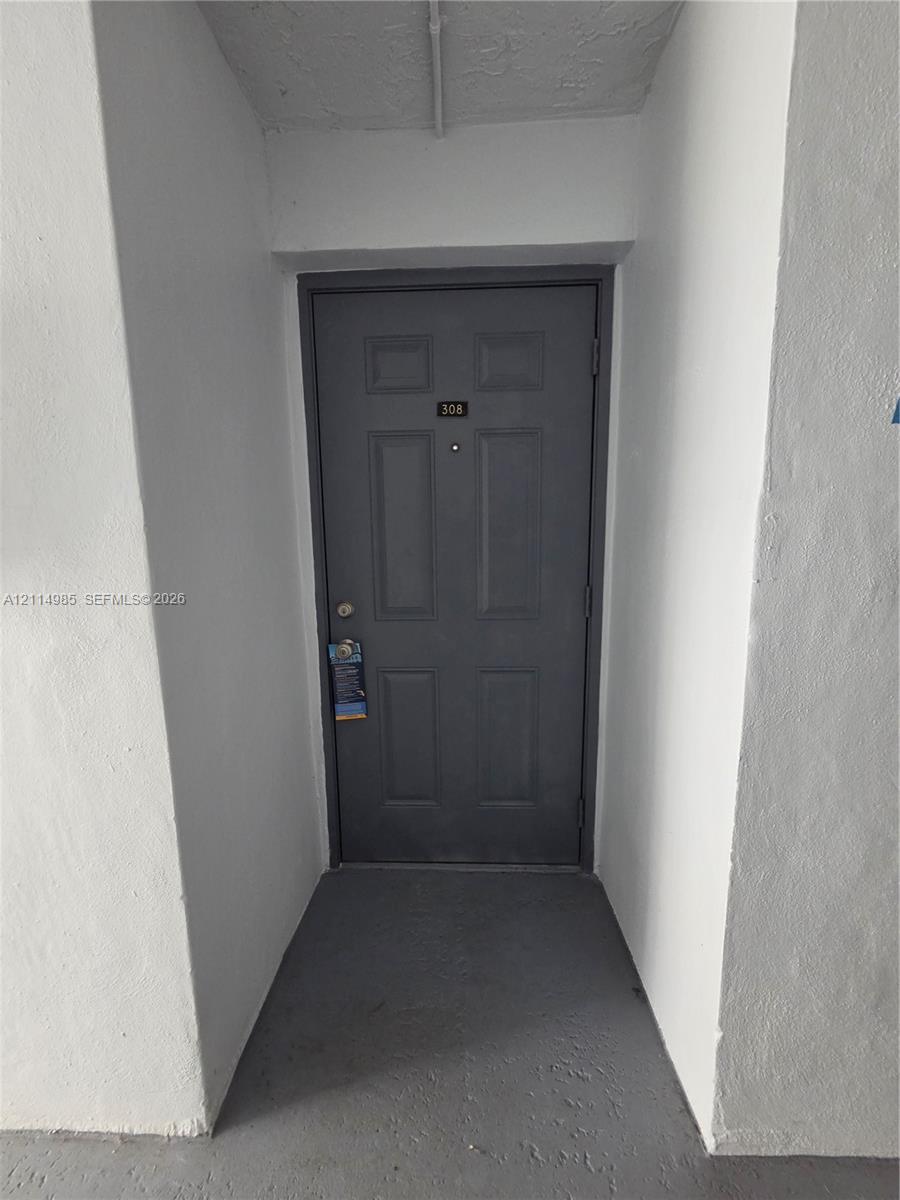 Six-panel entry door featuring a matte finish, a deadbolt lock, and a centered peephole