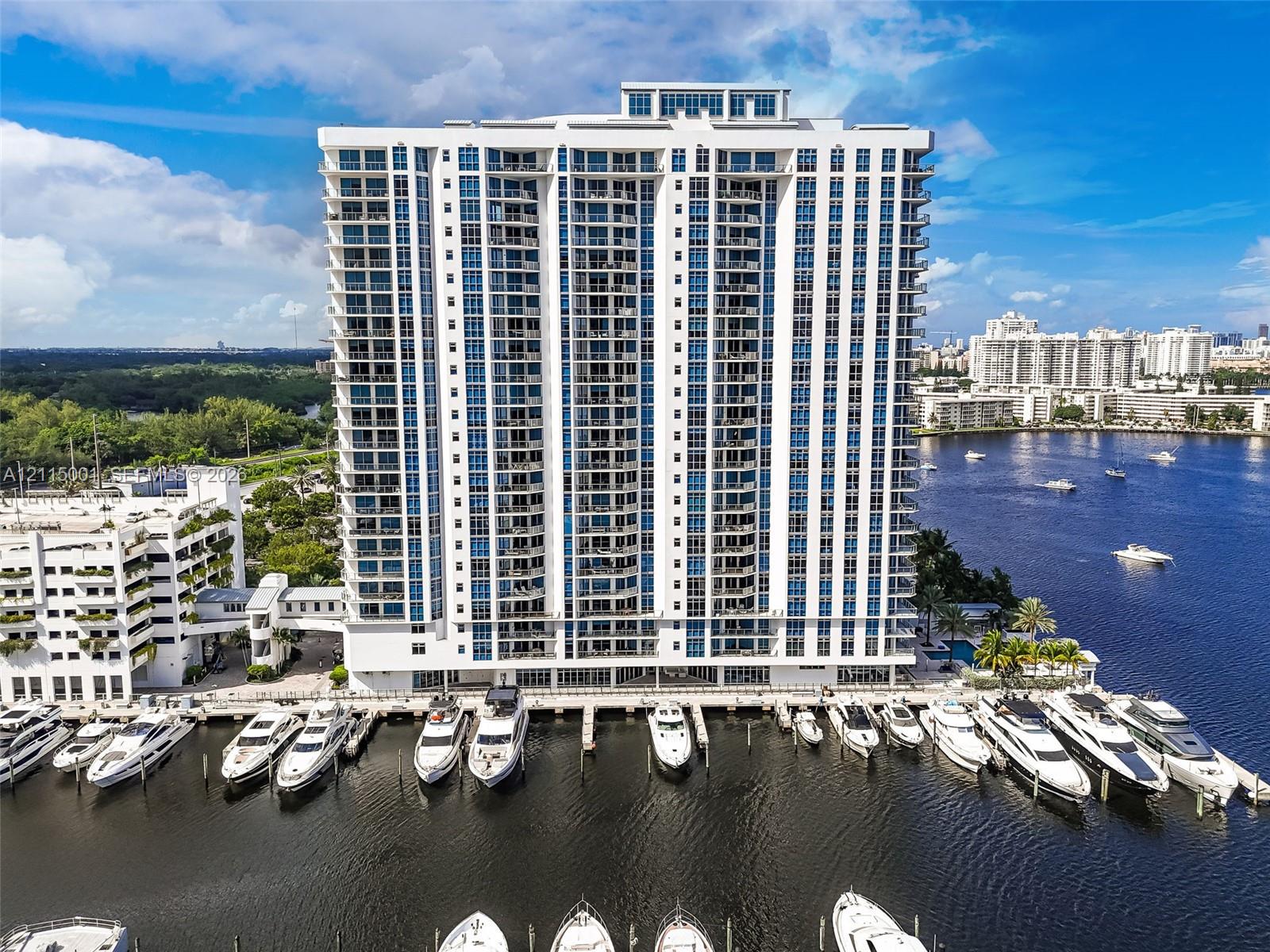 High-rise residential building featuring floor-to-ceiling windows, private balconies, and an attached deep-water marina