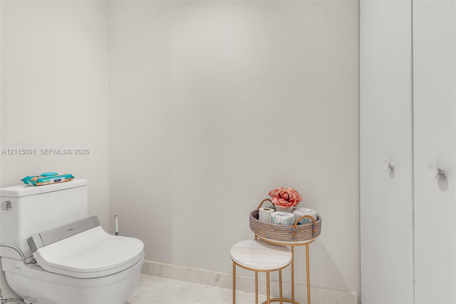 White dual-flush toilet with integrated bidet seat and double-door cabinetry featuring round knob hardware