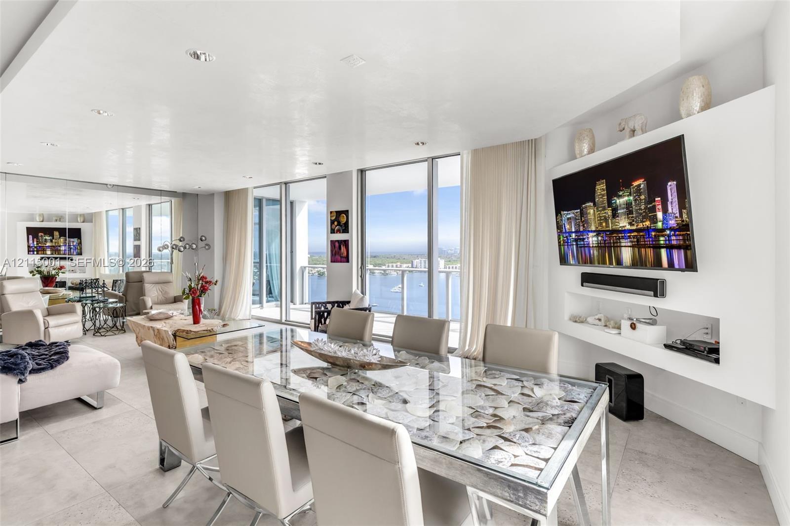 Open-concept living space featuring floor-to-ceiling windows, recessed lighting, large-format tile flooring, a custom built-in white media console, and an expansive balcony