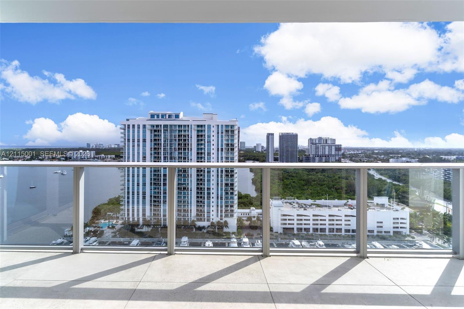 Covered balcony featuring expansive tile flooring and a transparent glass railing