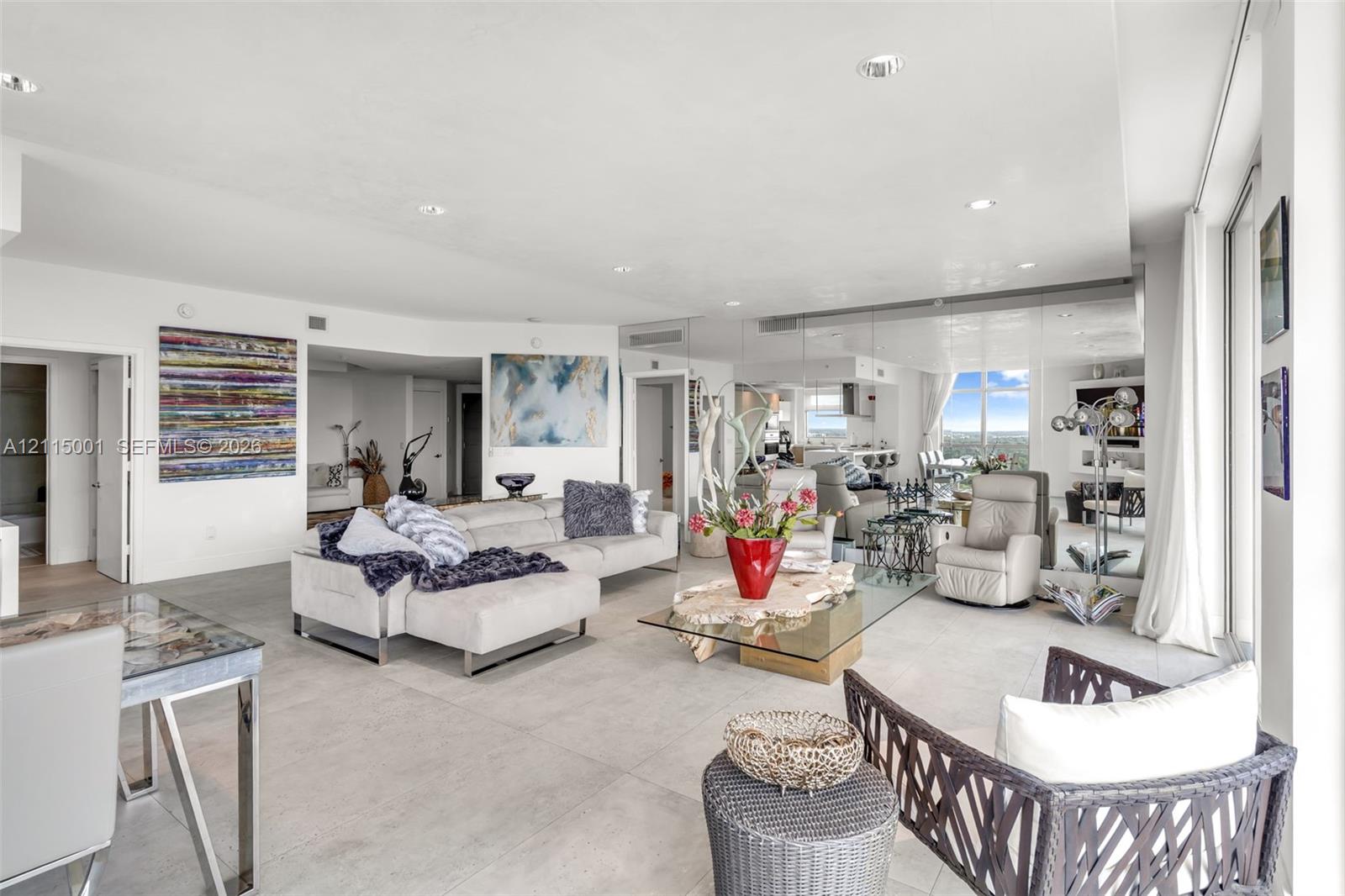 Open-concept interior featuring large-format tile flooring, recessed ceiling lighting, and floor-to-ceiling mirrored walls