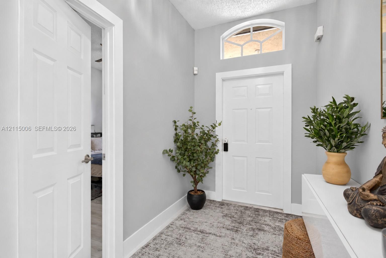 Entryway featuring a white paneled door, arched transom window, and neutral wall color Entryway featuring a white paneled door, arched transom window, and neutral wall color
