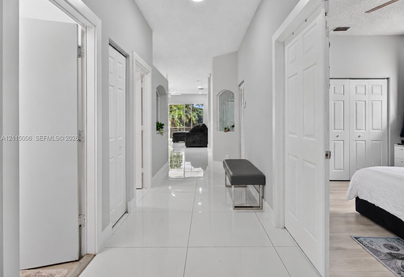 Hallway featuring glossy tile flooring, neutral wall color, arched wall niches, and paneled interior doors Hallway featuring glossy tile flooring, neutral wall color, arched wall niches, and paneled interior doors