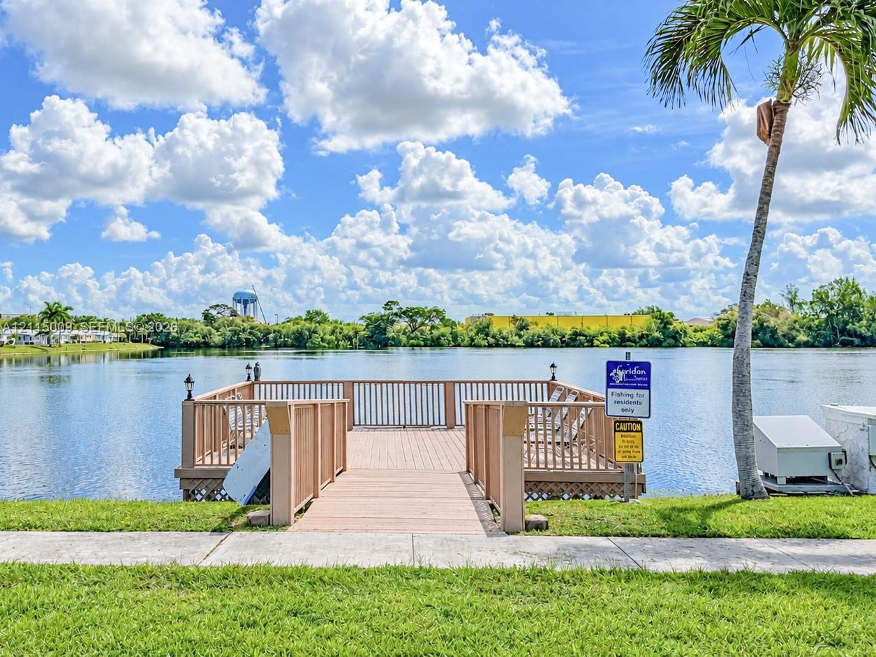 Waterfront wooden pier featuring perimeter railings and concrete sidewalk access